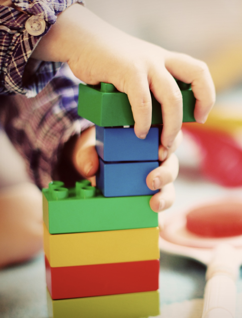 Legotornia rakentavan lapsen kädet.