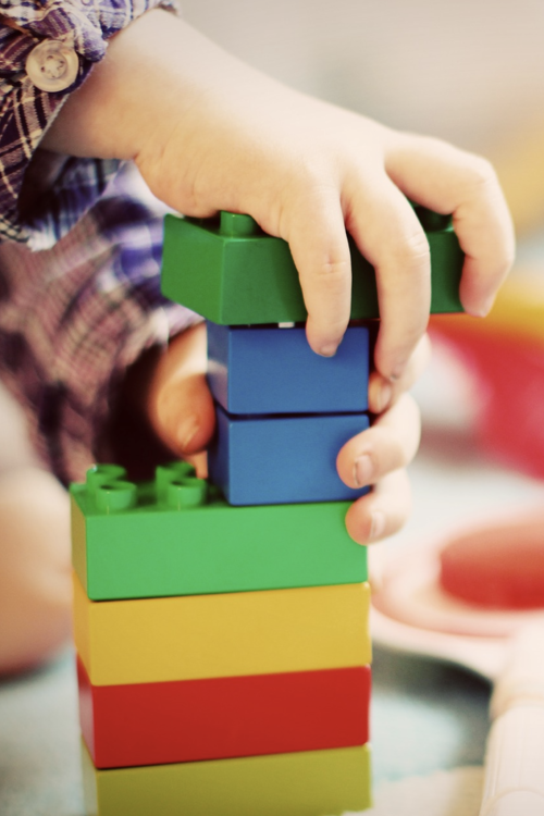 Legotornia rakentavan lapsen kädet.